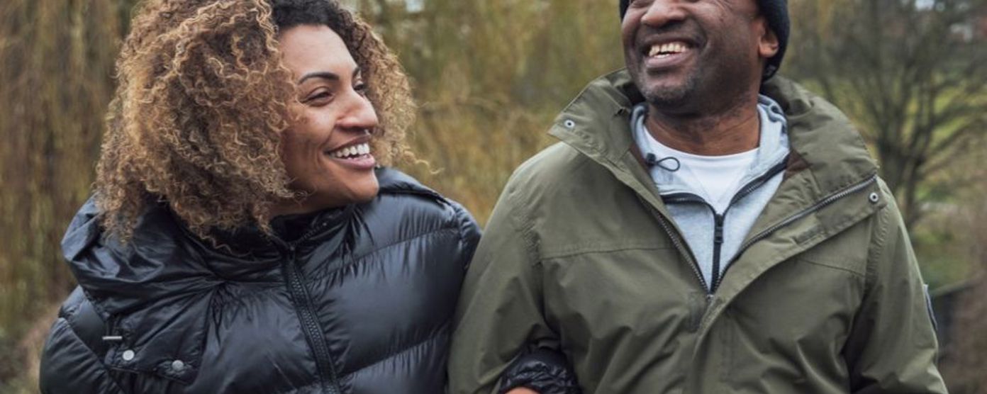 a couple happily walking along arm in arm in nature