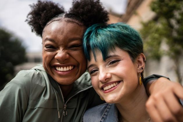Two females smiling at the camera - one has her arm around the other
