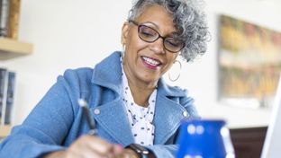 Professional woman taking notes while sitting at a table