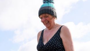 a very happy women wearing a beanie hat and a swimsuit